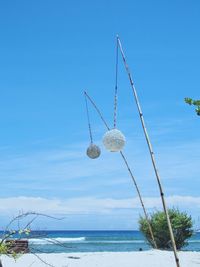 Ferris wheel hanging by sea against blue sky