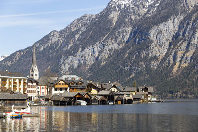 Houses by lake and mountains against sky