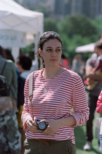 Close-up of beautiful young woman carrying camera