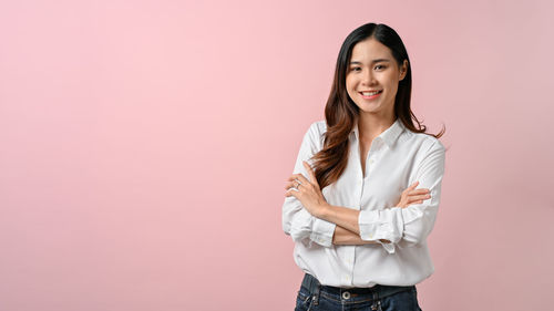 Portrait of young woman standing against yellow background