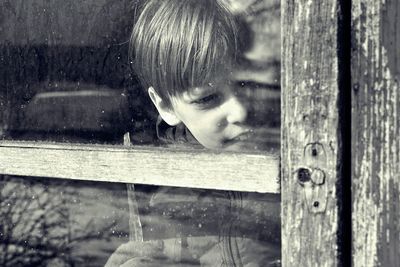 Close-up of boy looking through window