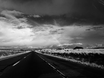 Country road against cloudy sky