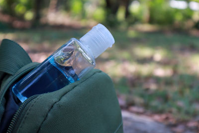 Close-up of man holding bottle by water
