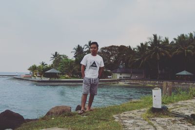 Full length of young man standing by sea against sky