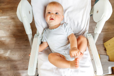 High angle view of cute baby boy sitting on slide at home