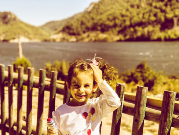 Portrait of smiling girl sitting on fence