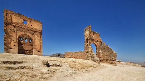 Low angle view of old ruins against clear blue sky