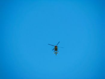 Low angle view of helicopter flying against clear blue sky