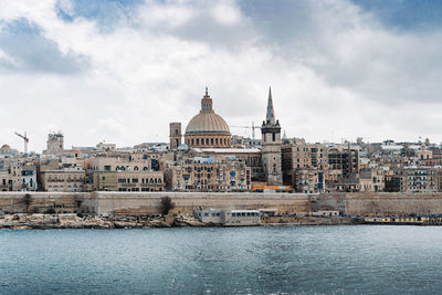 Buildings in city against cloudy sky