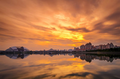 Sport hub and buildings by kallang lake against dramatic sky during sunset