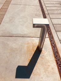 High angle view of shadow on footpath against building