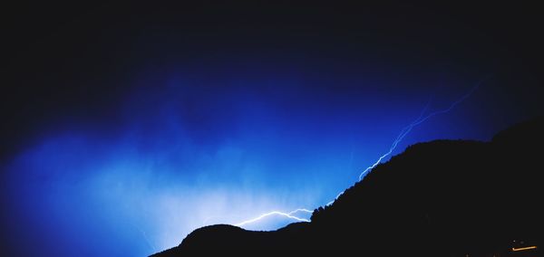 Low angle view of silhouette mountain against sky at night