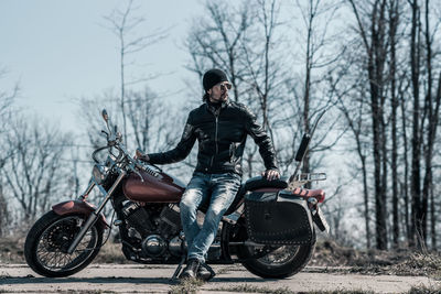 Mid adult man sitting on motorcycle in forest