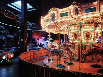 Illuminated carousel in amusement park at night