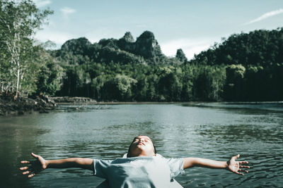 Boy in boat at lake against sky