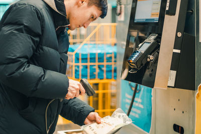 A young guy punches the goods at the checkout in the store.