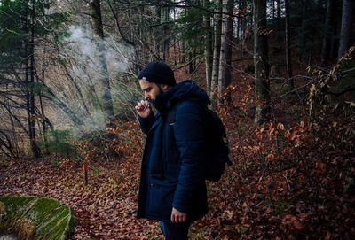 Side view of young man standing in forest