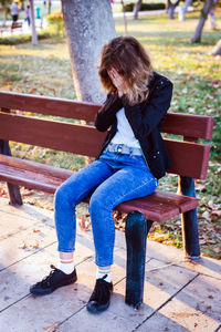Sad teenager girl sitting on the bench in autumn park. crying young girl in depression

