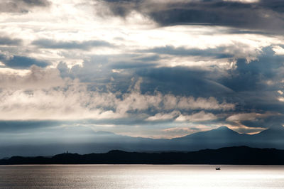 Scenic view of river against cloudy sky during sunny day