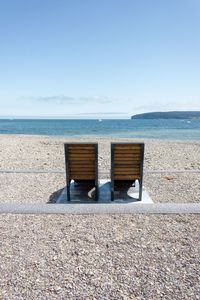 Empty chair on beach against sky