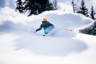 Man skiing on snowcapped mountain against trees
