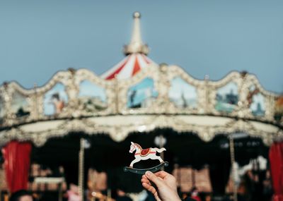 Close-up of hand holding toy against carousel 