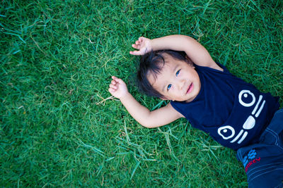 High angle view of boy lying on grassy field