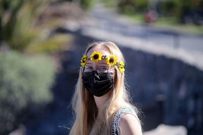 Portrait of young woman wearing mask and wreath outdoors