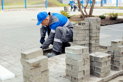 Bricklayer lays paving slabs outside. working man performs landscaping. builder lays out sidewalk