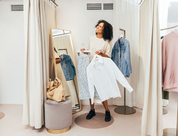 Smiling woman trying dress at clothing store