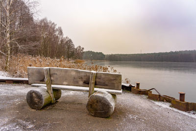 Bench by lake against clear sky