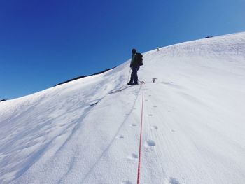 Man skiing on snowcapped mountain against clear sky