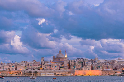 Buildings in city against cloudy sky