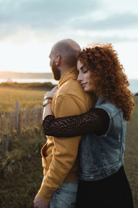 Side view of couple kissing against sky