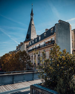 Building by trees against sky in city