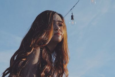 Close-up of young woman against sky