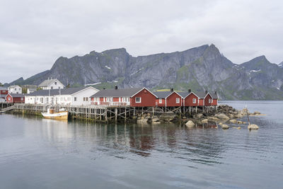 Houses by lake and mountains against sky