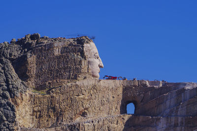 Low angle view of rock formation against clear blue sky