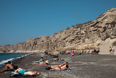 Group of people on rocks against clear sky