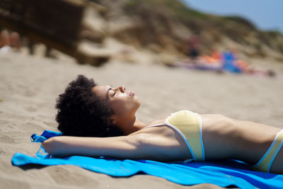 Portrait of young woman lying on bed at beach