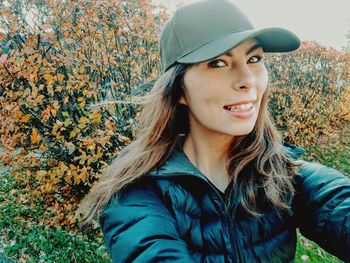 Portrait of smiling young woman standing outdoors during autumn