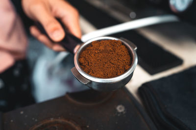 Cropped hand of person holding coffee powder in container