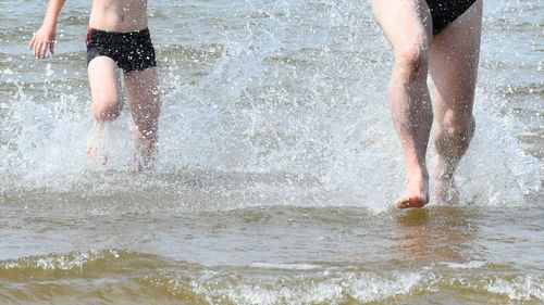 Low section of man standing on wet beach