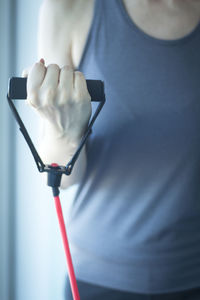 Midsection of woman exercising with resistance band in gym