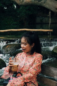 Young woman drinking coffee at riverbank