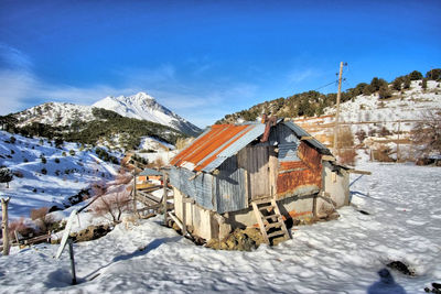 Houses on snowcapped mountain against blue sky