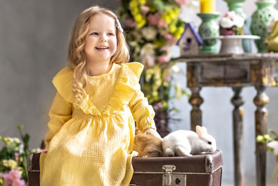 A  toddler girl in a yellow dress  with rabbits .emotions. bright holiday of easter