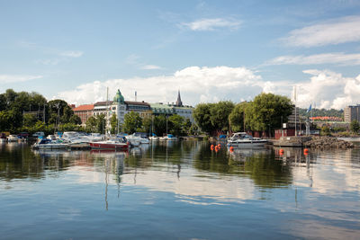 Boats at lake against sky in city