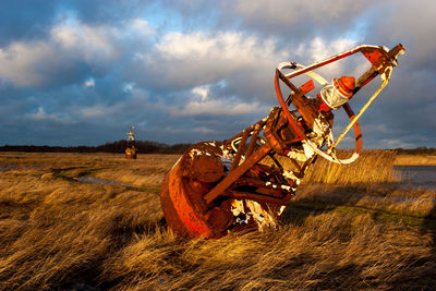 Rusty metallic structure on field against sky