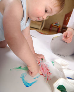 Cute baby boy painting with sister on paper